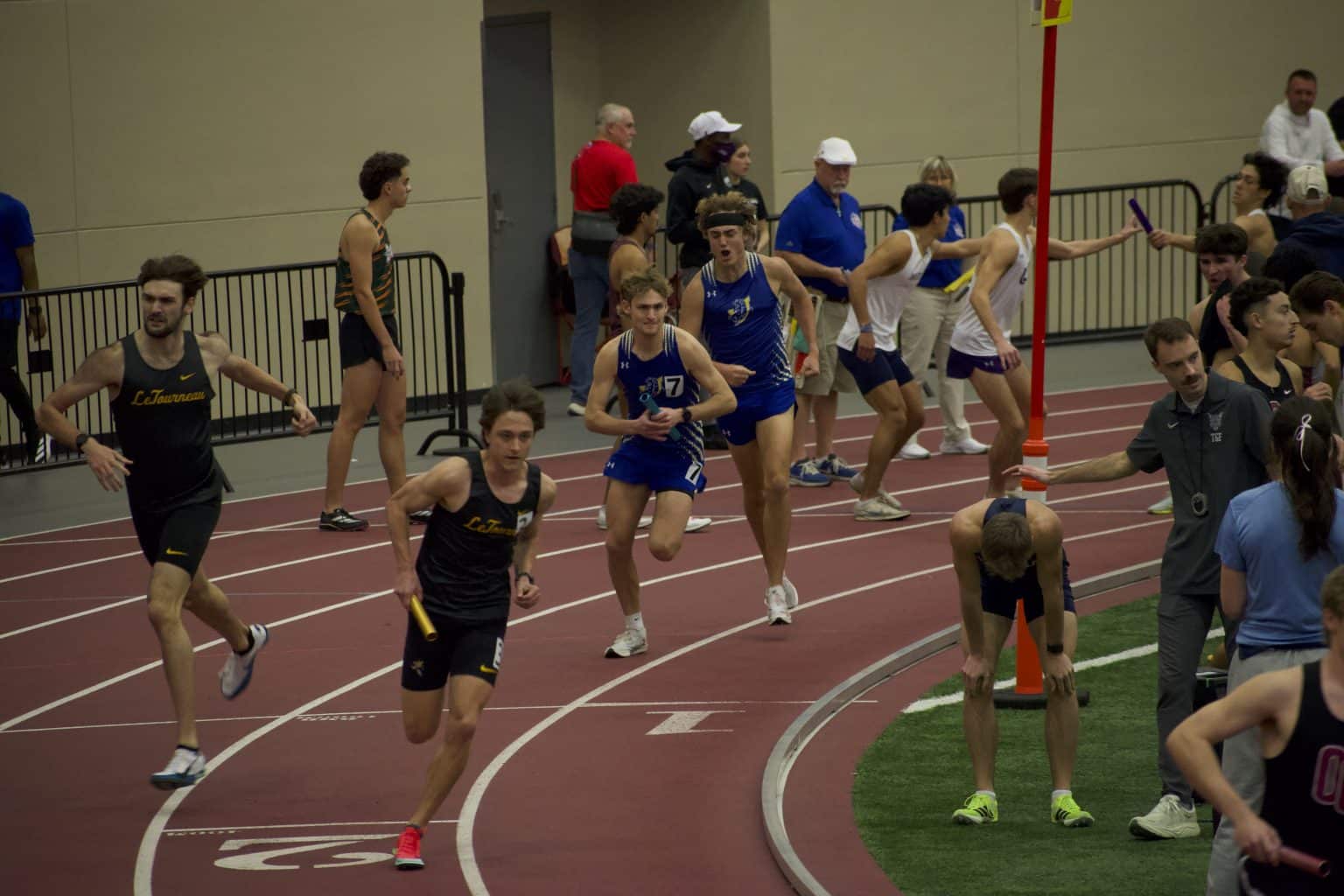 Mulerider runners in blue take the baton during an indoor relay race